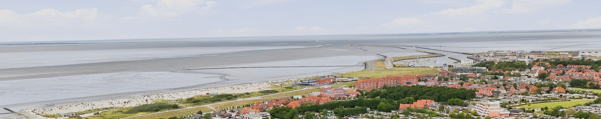 Luftaufnahme von Norddeich mit Strand, Deich und Ferienwohnungen, vermietet vom Ferienlotse Nordsee